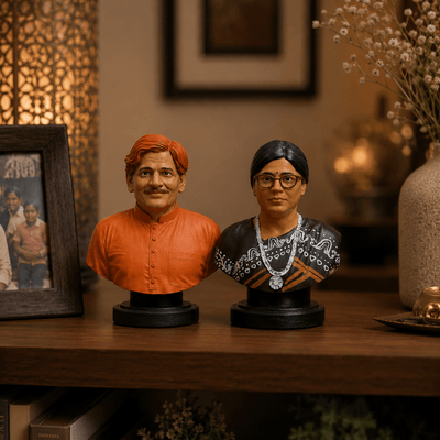 Two busts of a man and a woman on a wooden surface with a blurred background